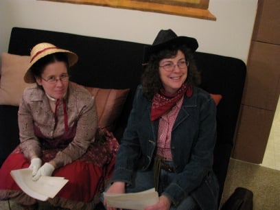 Who Shot the Sheriff – Ruby-Mae Marshall and Jessie Calhoun watch the rest of their motley crowd enter the Gold Nugget Saloon 
								– Tara Laben